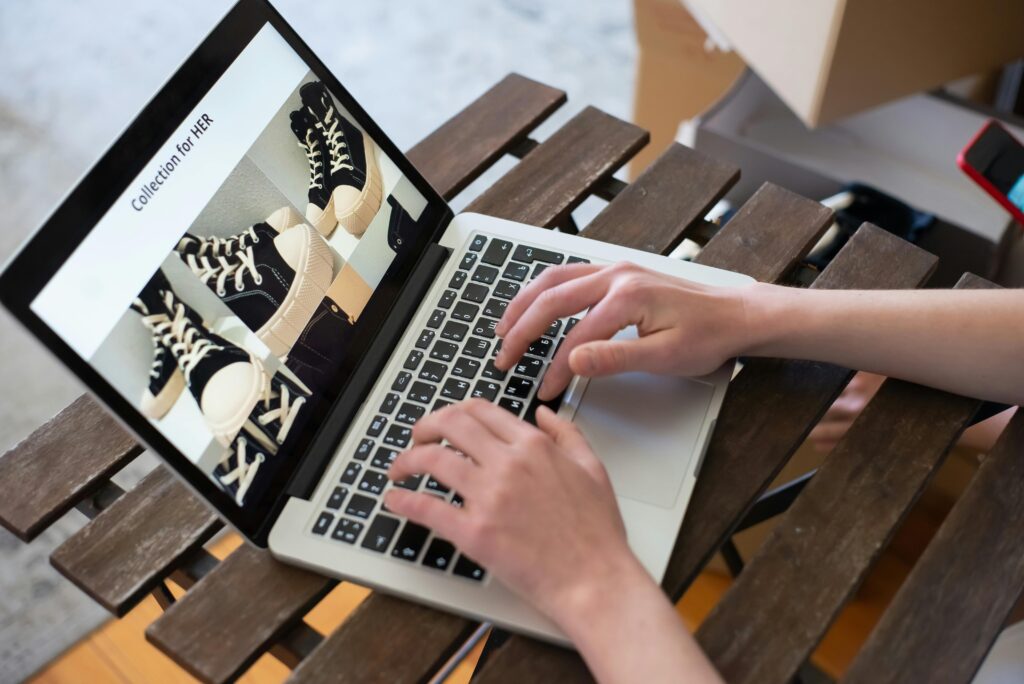 Hands of a person browsing a Collection for HER on an online shoe store using a laptop.